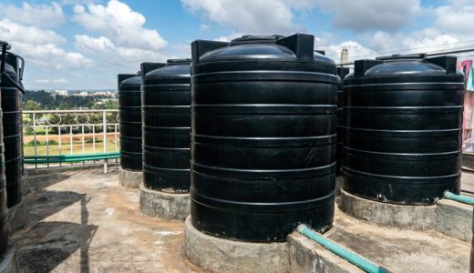 city roofs are occupied by black water storage tanks. Water tank on roof in Africa. Water heating tank against sea and the city. Asian water supply and heating system