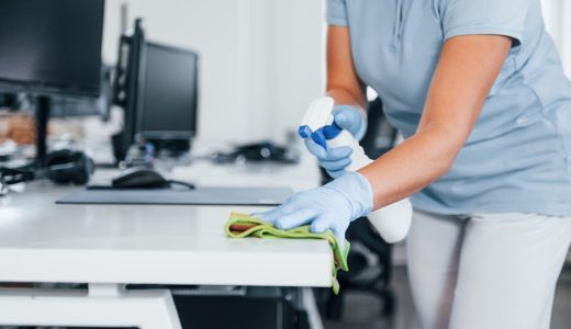 Close up view of woman in protective gloves that cleaning tables in the office.