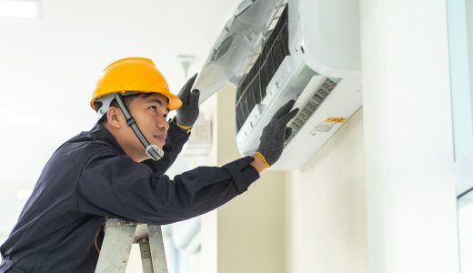 Male technician repairing air conditioner safety uniform indoors.