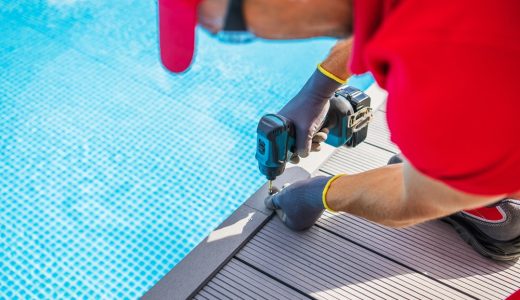 Poolside Composite Deck Building by Professional Worker. Modern Swimming Pool Surrounding. Using Cordless Drill Driver.